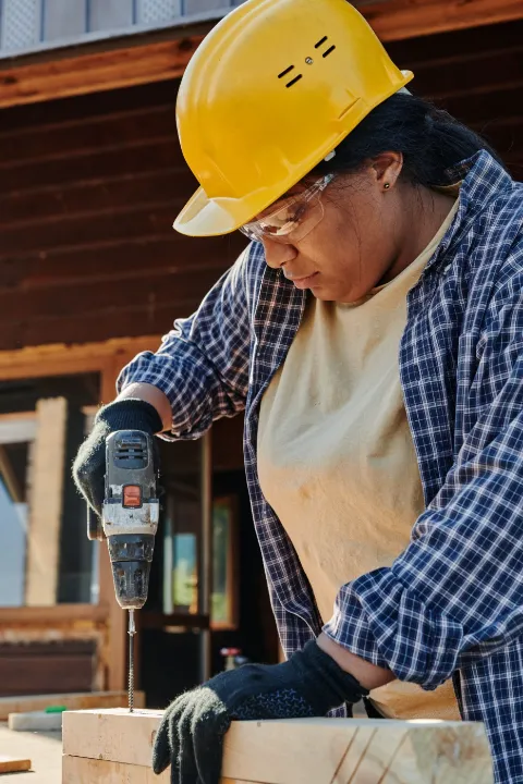 Carpenter driving a screw into a beam