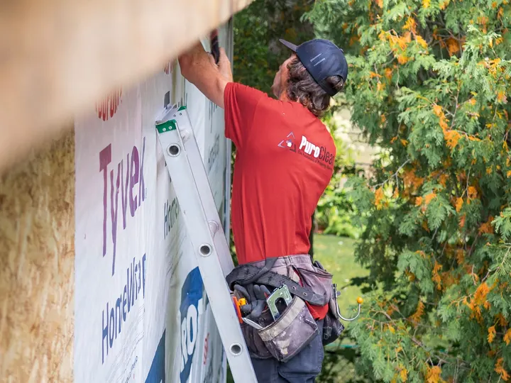 Pro fitting house wrap from a ladder